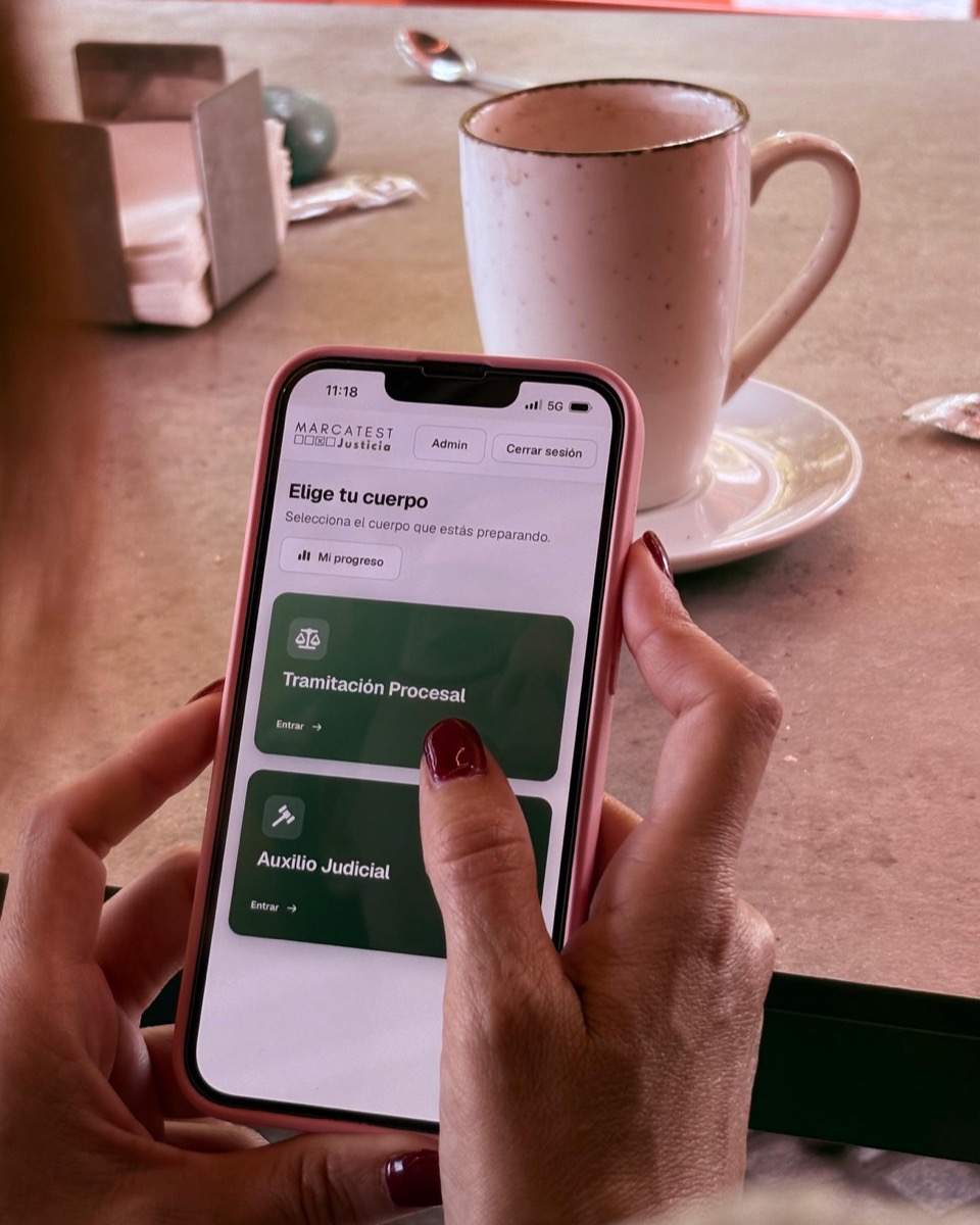 Opositora usando MarcaTest en el móvil con un café